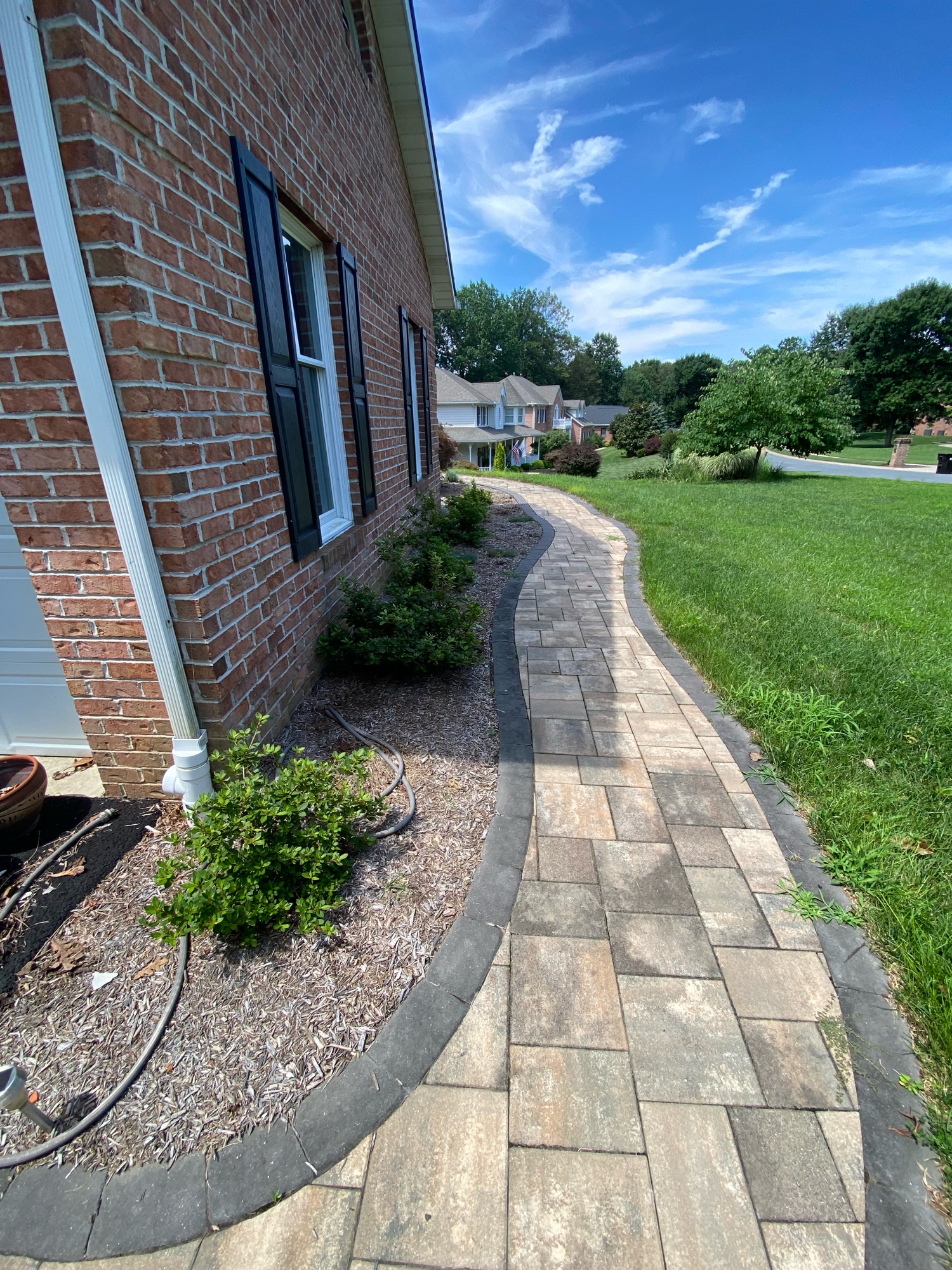Curved stone retaining wall with large freshly cut green lawn